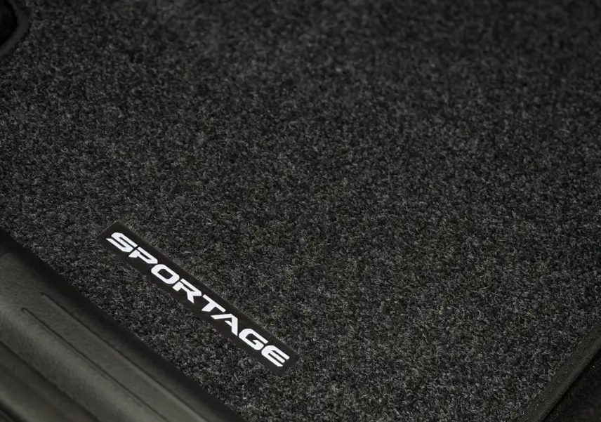 Gros plan sur le tapis de sol noir avec l'inscription blanche "SPORTAGE" du KIA Sportage 2025 gris perle.