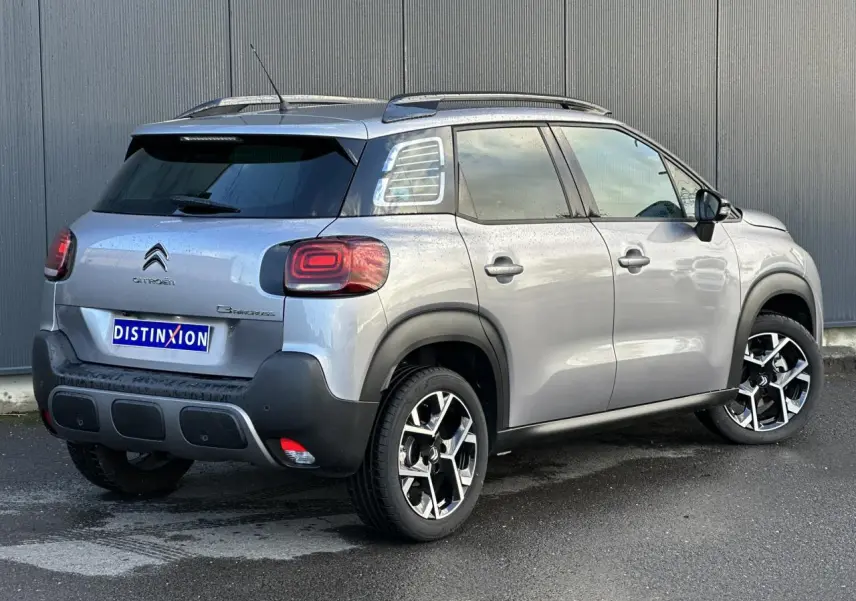 Vue 3/4 arrière droite d’un Citroën C3 Aircross gris Artense avec barres de toit et jantes alliage 17 pouces.