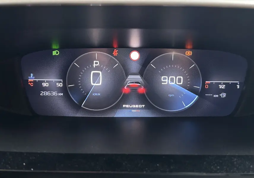 Tableau de bord numérique de Peugeot 308 2024 affichant vitesse, régime moteur, température et alertes au centre.