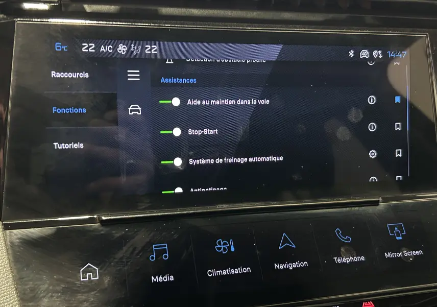Écran tactile central de la Peugeot 308 rouge 2024 montrant les assistances à la conduite et les options multimédia.