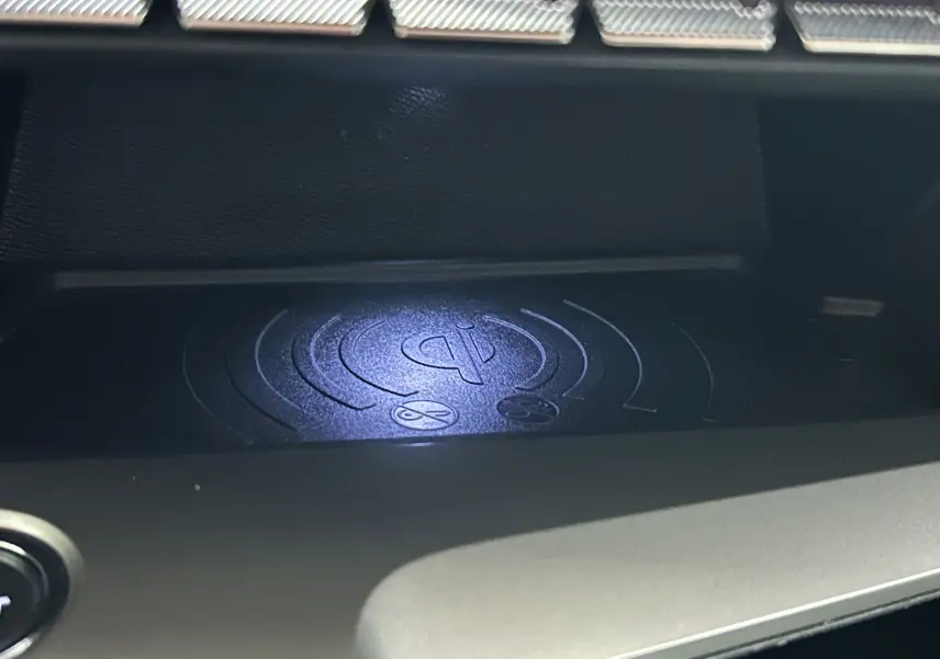 Gros plan sur le chargeur à induction dans l'habitacle de la Peugeot 308 rouge 2024, version Allure.