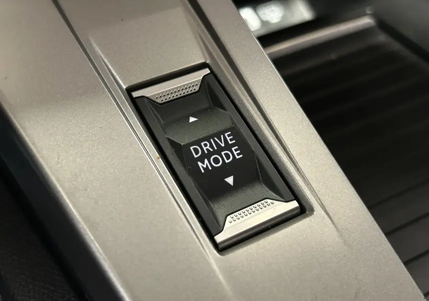 Gros plan sur le bouton Drive Mode au centre de la console intérieure grise de la Peugeot 308 2024.