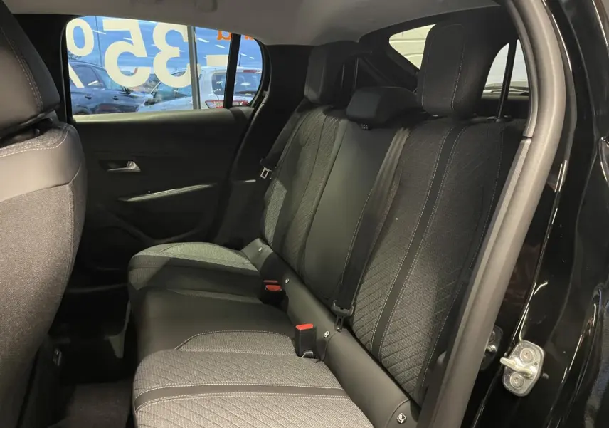 Vue intérieure côté droit de la banquette arrière noire et tissu gris d’une Peugeot 208 1.2i Hybrid 2025 noire métallisée.