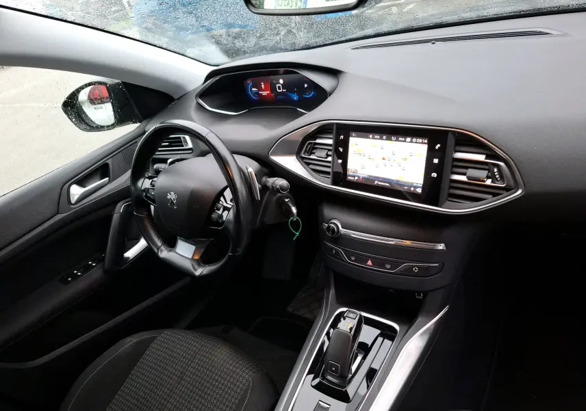 Vue intérieure côté gauche du tableau de bord noir de la Peugeot 308 SW avec écran tactile et volant multifonction.