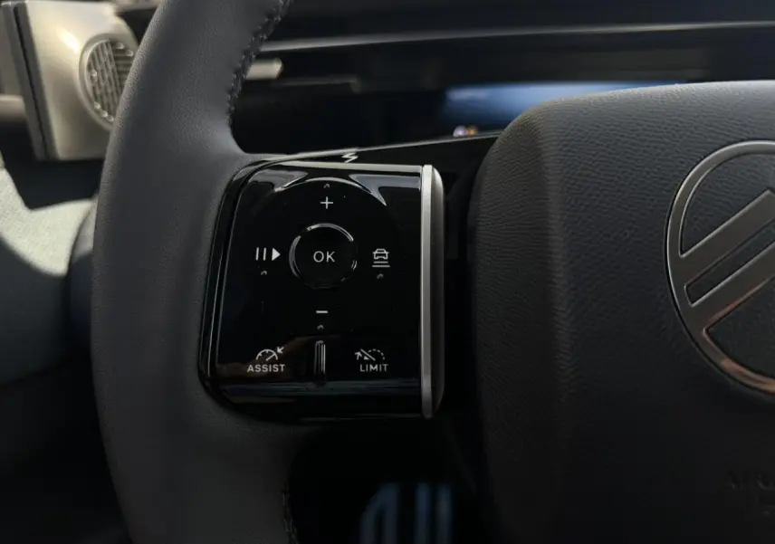 Gros plan sur la commande multifonction gauche du volant noir du Citroën C5 Aircross 2026, avec logo central visible.