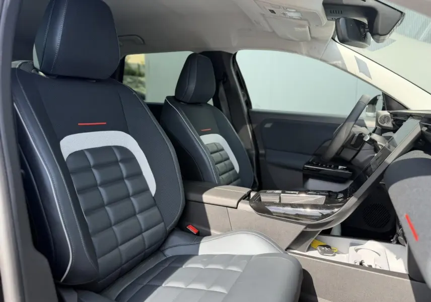 Intérieur de la Citroën C5 Aircross 2026, vue côté droit sur sièges noirs et gris avec surpiqûres blanches et accoudoir central.