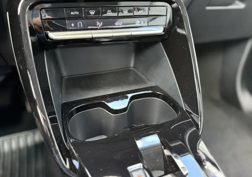 Détail de la console centrale noire du Citroën C3 Aircross Hybrid 145, avec commandes climatisation et porte-gobelets.