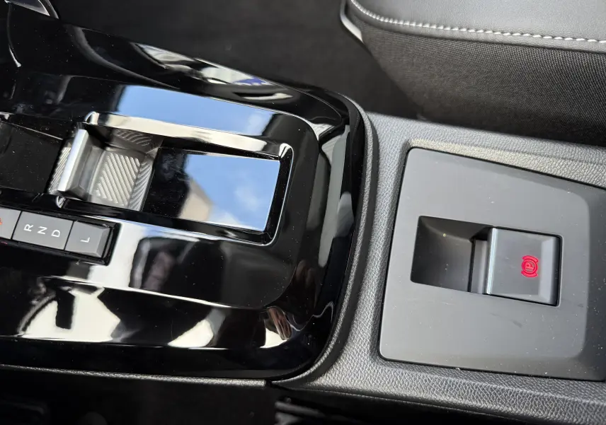 Gros plan sur la console centrale noire brillante de la Citroën C3 Aircross Hybrid 145, avec levier de vitesses automatique et frein à main électronique.