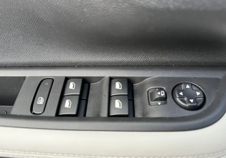 Gros plan sur les commandes de lève-vitres et réglage des rétroviseurs côté conducteur d'une Citroën C3 Aircross blanc banquise toit noir.