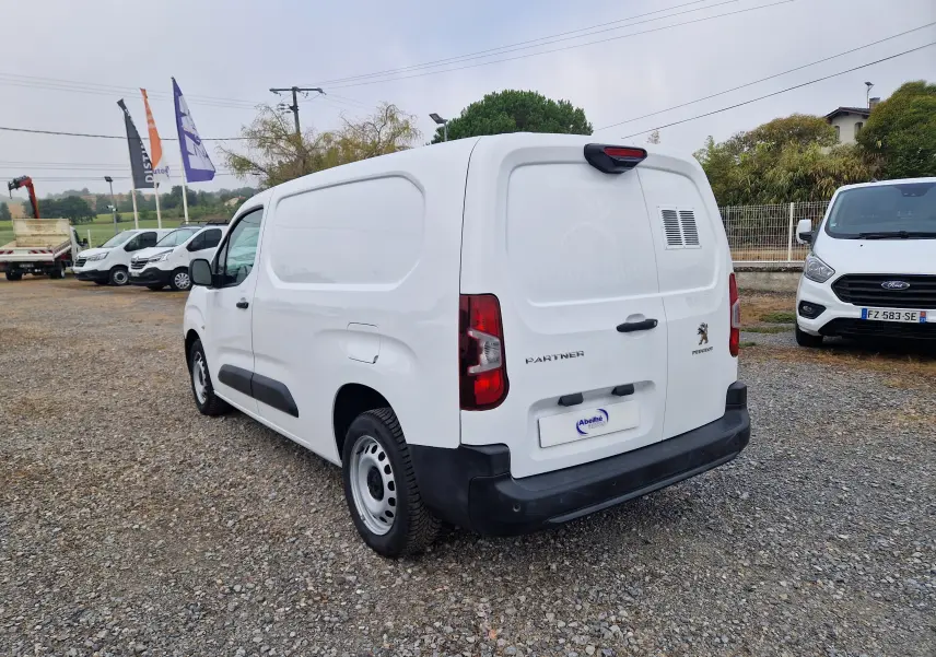 Vue 3/4 arrière droite d'un Peugeot Partner blanc 2021 utilitaire avec porte arrière ventilée et pare-chocs noir.