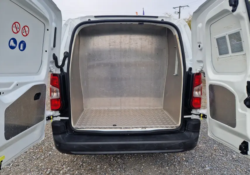Vue arrière du Peugeot Partner blanc 2021 avec portes ouvertes, montrant l'espace de chargement métallique vide.