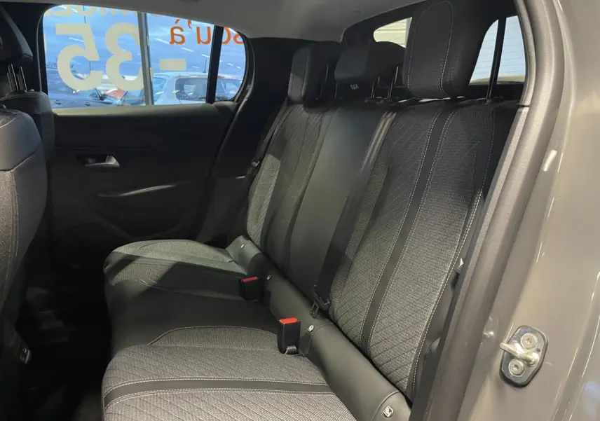 Vue intérieure arrière côté droit de la Peugeot 208 gris selenium, montrant la banquette tissu avec surpiqûres contrastées.