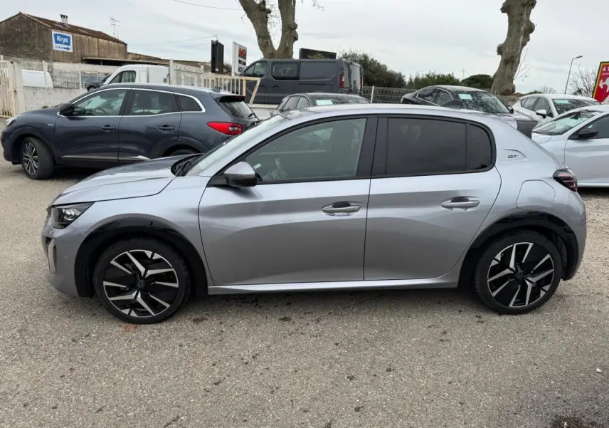 Vue de profil côté gauche d'une Peugeot 208 gris clair Hybrid 110 e-DCS6 GT avec jantes alliage 17 pouces et vitres teintées.