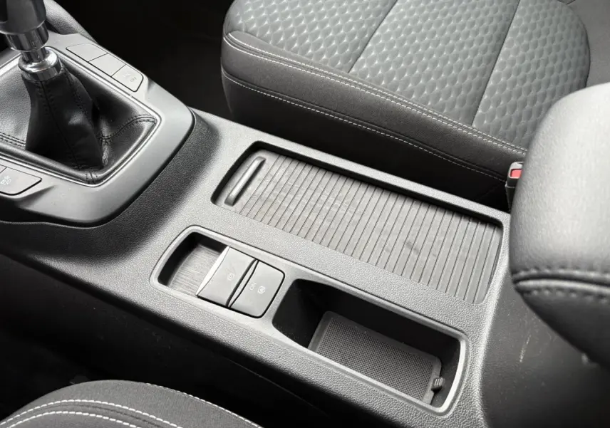 Vue rapprochée de la console centrale noire avec levier de vitesses manuel et siège avant tissu gris du Ford Kuga 2024.