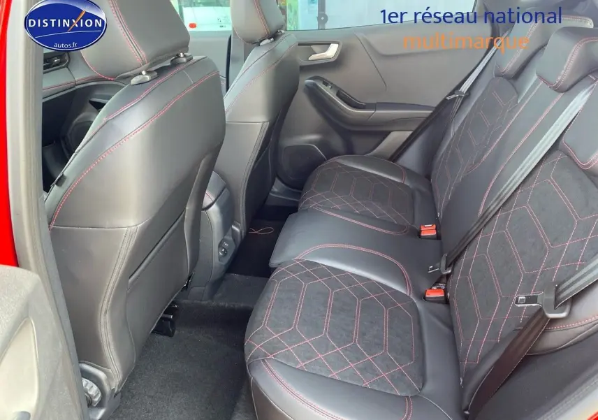 Vue intérieure arrière côté gauche du Ford Puma rouge, sièges en tissu noir avec surpiqûres rouges et détails cuir.