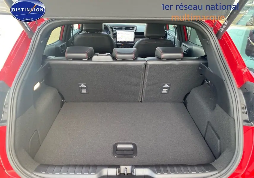 Coffre ouvert vu de l'arrière d'un Ford Puma rouge métallisé avec banquette arrière et tableau de bord visibles.