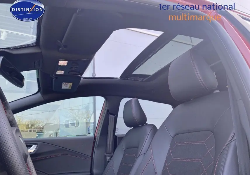 Vue intérieure côté conducteur du Ford Puma rouge avec toit ouvrant panoramique et sièges sport noirs à surpiqûres rouges.