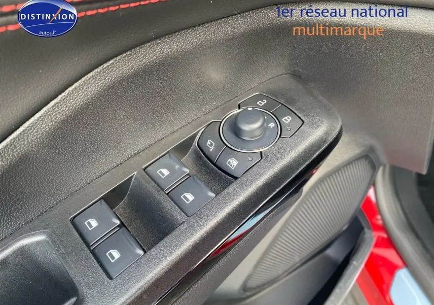 Gros plan sur la commande des vitres et rétroviseurs côté conducteur d'une Ford Puma rouge métallisée.