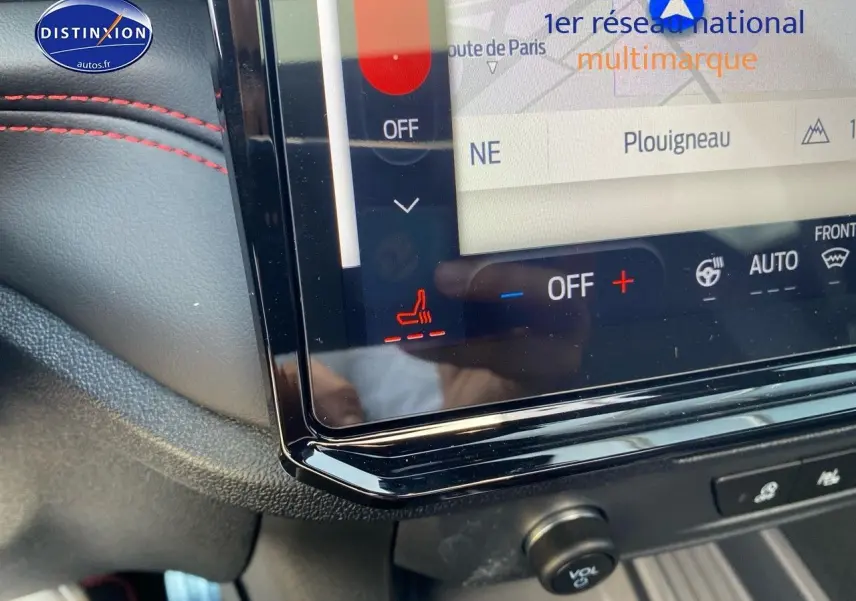 Détail de l’écran tactile central du Ford Puma rouge avec commandes de climatisation et sièges chauffants, intérieur noir avec surpiqûres rouges.