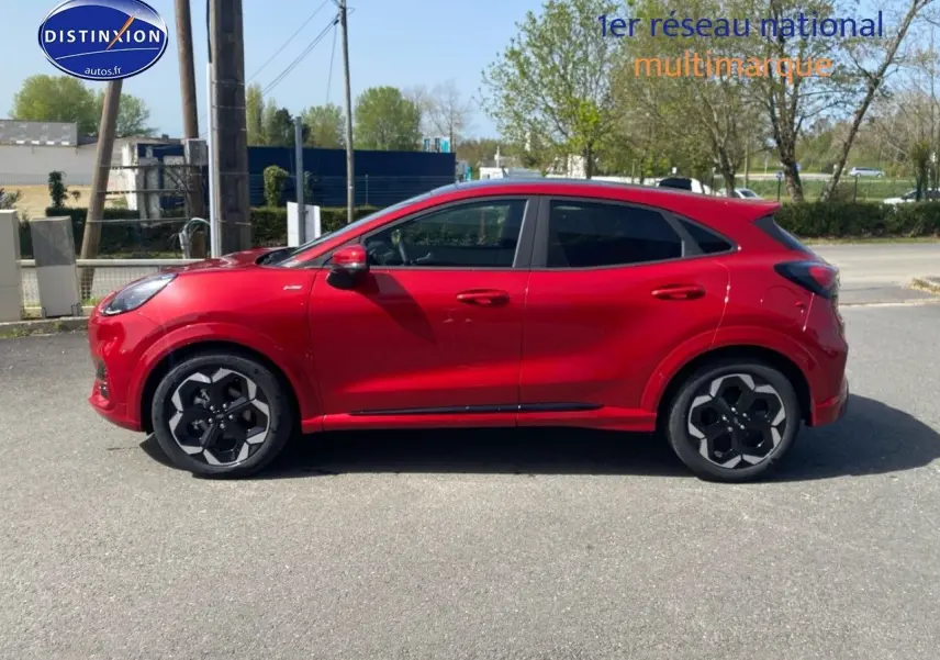 Vue de profil côté gauche d'un Ford Puma rouge métallisé avec jantes alliage noires et toit ouvrant panoramique.