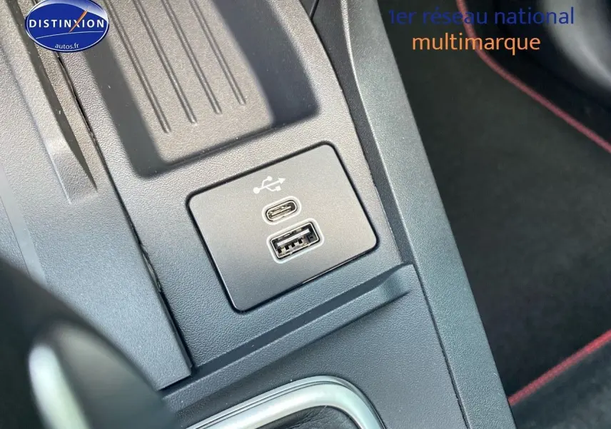 Vue rapprochée du port USB-C et USB-A sur la console centrale du Ford Puma rouge, avec surpiqûres rouges visibles.