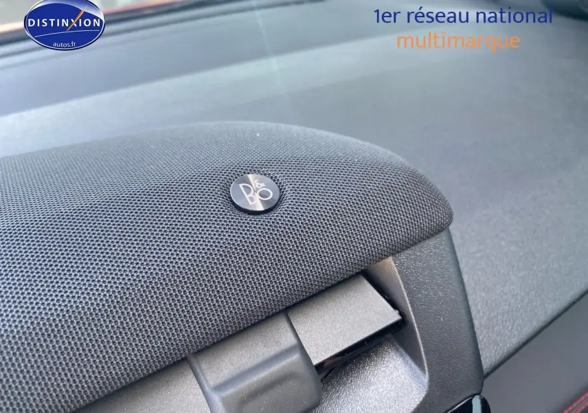 Détail du haut-parleur Bang & Olufsen intégré au tableau de bord du Ford Puma rouge, vue intérieure rapprochée.