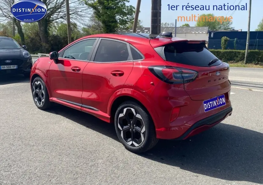 Vue 3/4 arrière droite d'une Ford Puma rouge métallisée avec jantes alu et vitres arrière surteintées.