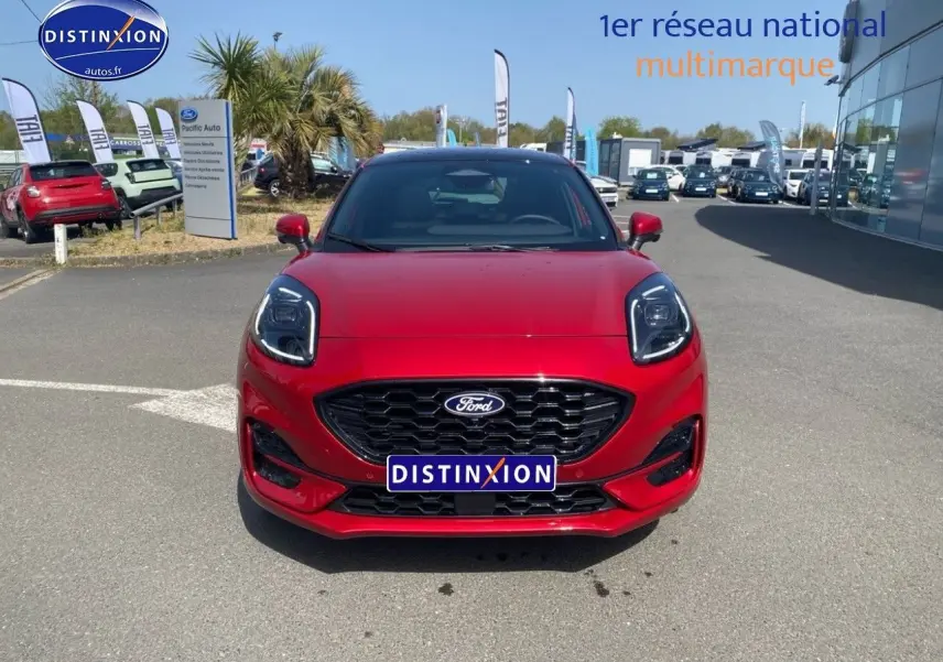 Vue avant d'un Ford Puma rouge métallisé avec calandre noire et phares LED, stationné en extérieur sur parking.