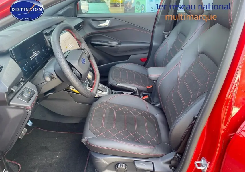 Vue intérieure côté conducteur du Ford Puma rouge, mettant en valeur les sièges sport noirs avec surpiqûres rouges et le volant multifonction.