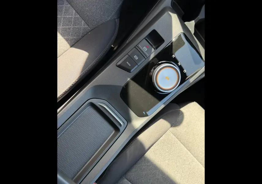Gros plan sur la console centrale noire avec sélecteur rotatif de boîte auto et tissu gris des sièges du MG3 1.5 Hybrid+ 2025.