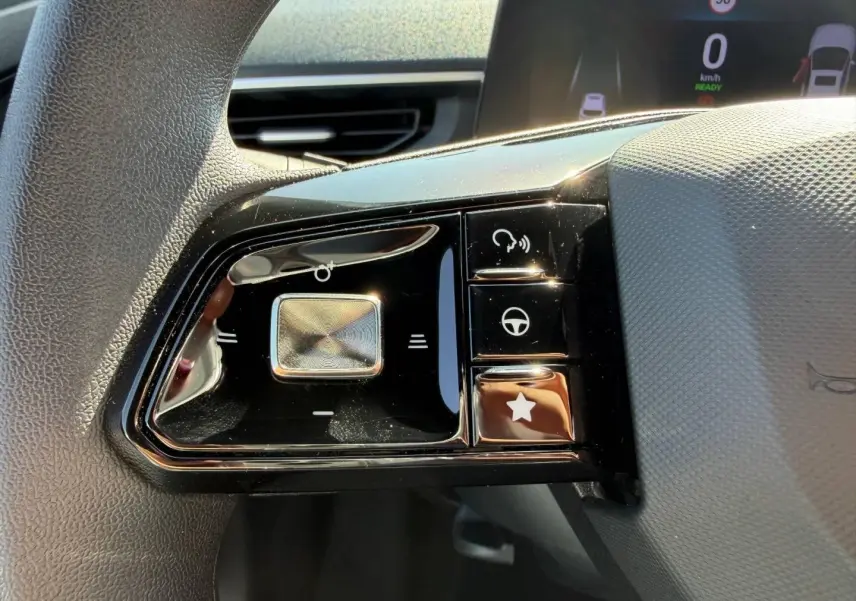 Gros plan sur les commandes noires brillantes du volant multifonction du MG3 1.5 Hybrid+ 2025, avec touches tactiles.