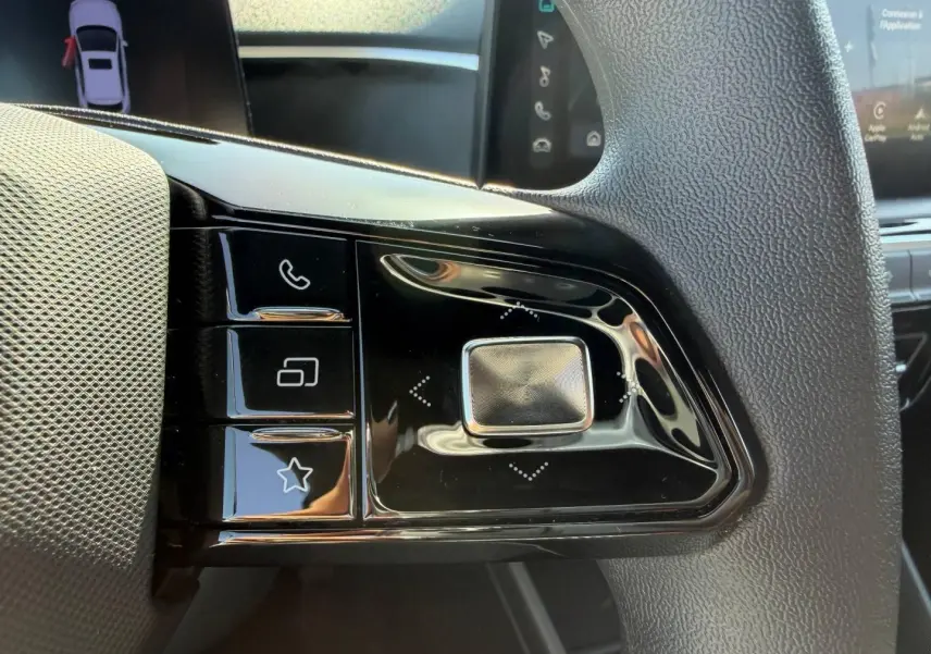 Gros plan sur les commandes multifonctions noires à gauche du volant de la MG3 1.5 Hybrid+ 2025, intérieur noir.