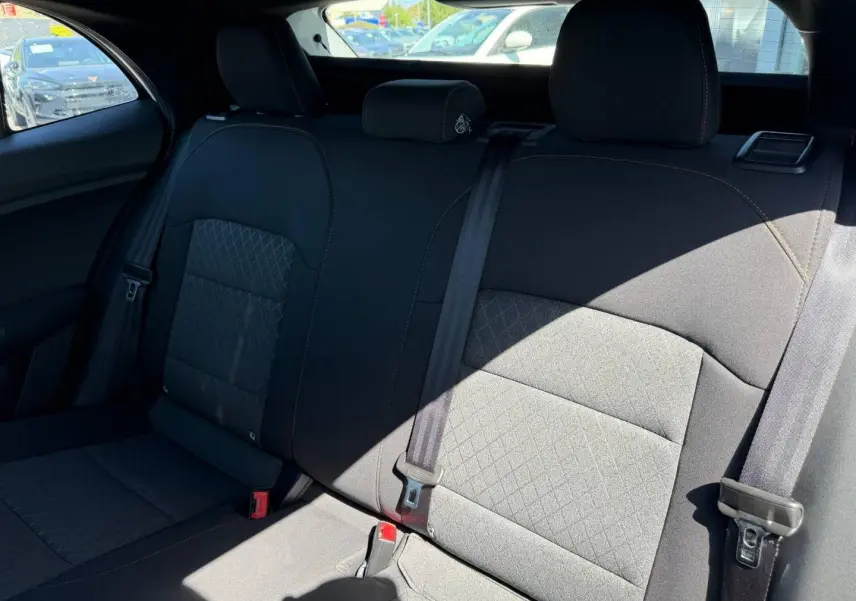 Vue intérieure de la banquette arrière noire en tissu du MG3 1.5 Hybrid+ 195ch Comfort, avec ceintures de sécurité visibles.