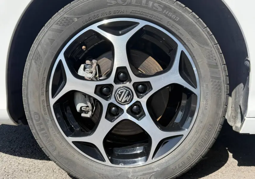 Gros plan sur la jante alu noire et argentée avec logo MG d’une MG3 blanche, vue côté roue avant droite.
