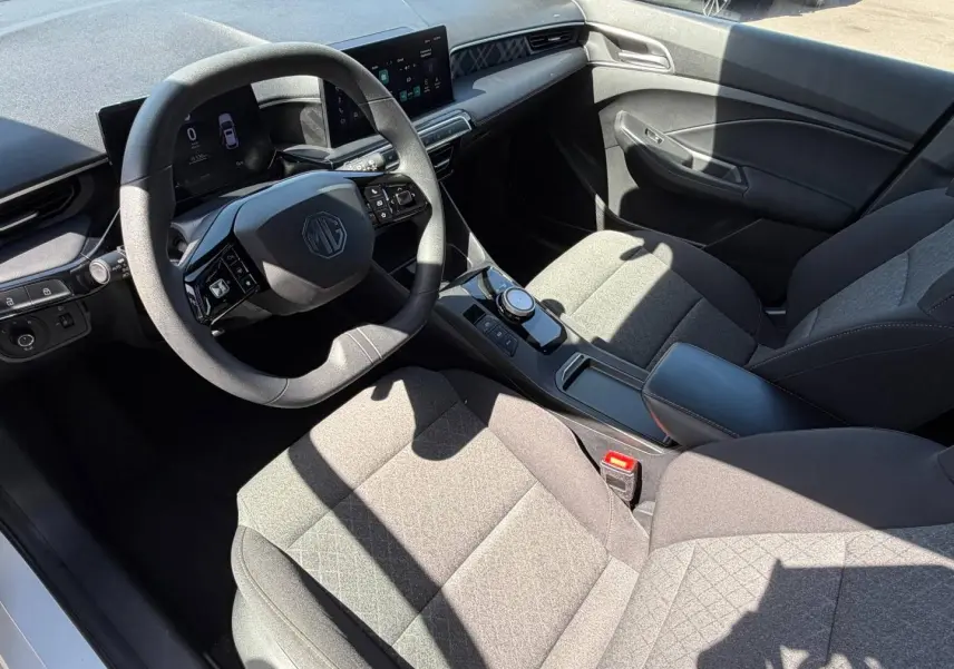 Vue intérieure côté conducteur du MG3 1.5 Hybrid+ 2025 avec sièges tissu gris et volant multifonction noir.