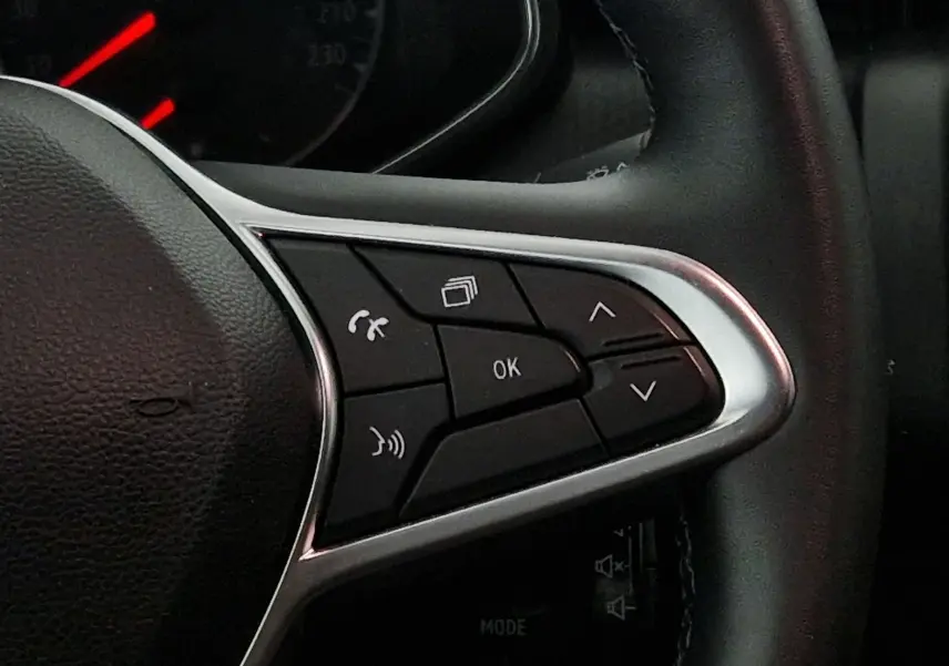 Gros plan sur les commandes multifonctions à droite du volant noir de la Renault Clio V gris platine, avec boutons de navigation et appel.