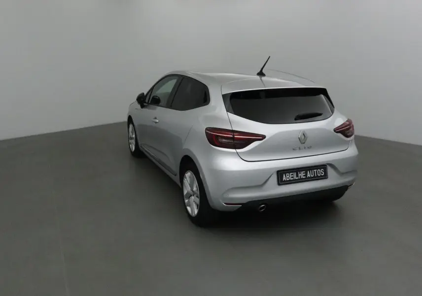 Renault Clio V gris platine vue 3/4 arrière côté gauche dans un studio avec vitres teintées et plaque Abeilhe Autos.