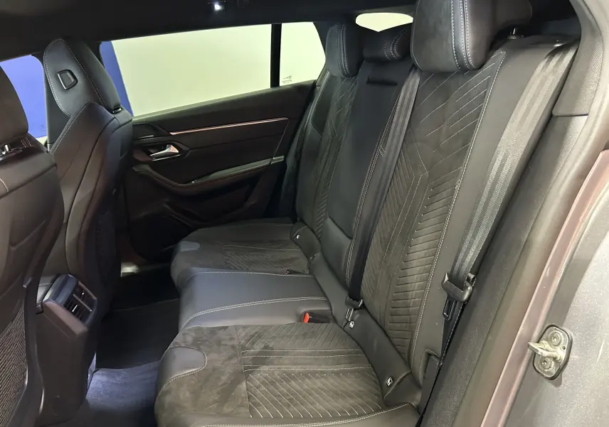Vue latérale droite de l'intérieur arrière du Peugeot 508 SW 2024, sièges en cuir et alcantara gris avec surpiqûres contrastées.