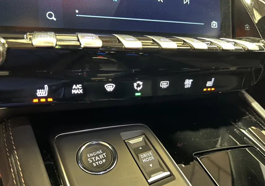 Gros plan sur la console centrale de la Peugeot 508 SW 2024, mettant en valeur les commandes de chauffage des sièges et le bouton start-stop.