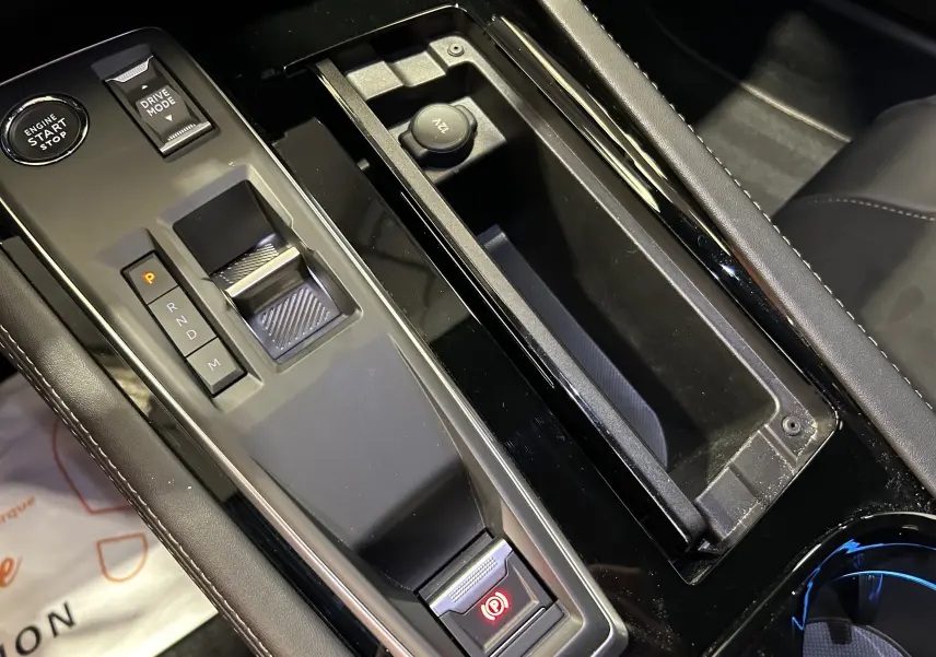 Gros plan sur la console centrale noire du Peugeot 508 SW 2024, montrant la commande de boîte auto et le frein à main électrique.