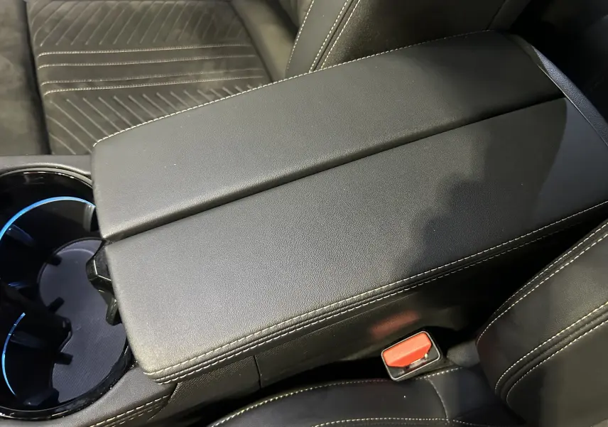 Gros plan sur l'accoudoir central en cuir noir avec surpiqûres blanches de la Peugeot 508 SW GT 2024.