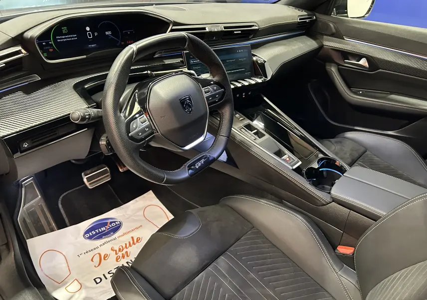 Intérieur moderne du Peugeot 508 SW 2024, vue côté conducteur sur le volant, tableau de bord numérique et sellerie cuir noire.