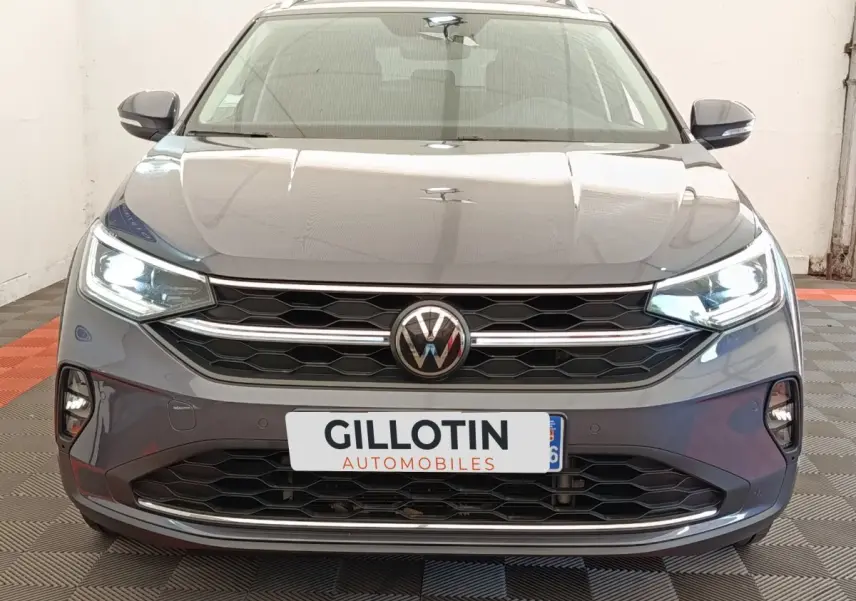 Vue frontale d’un Volkswagen Taigo gris foncé 2023 avec phares LED allumés et calandre hexagonale distinctive.