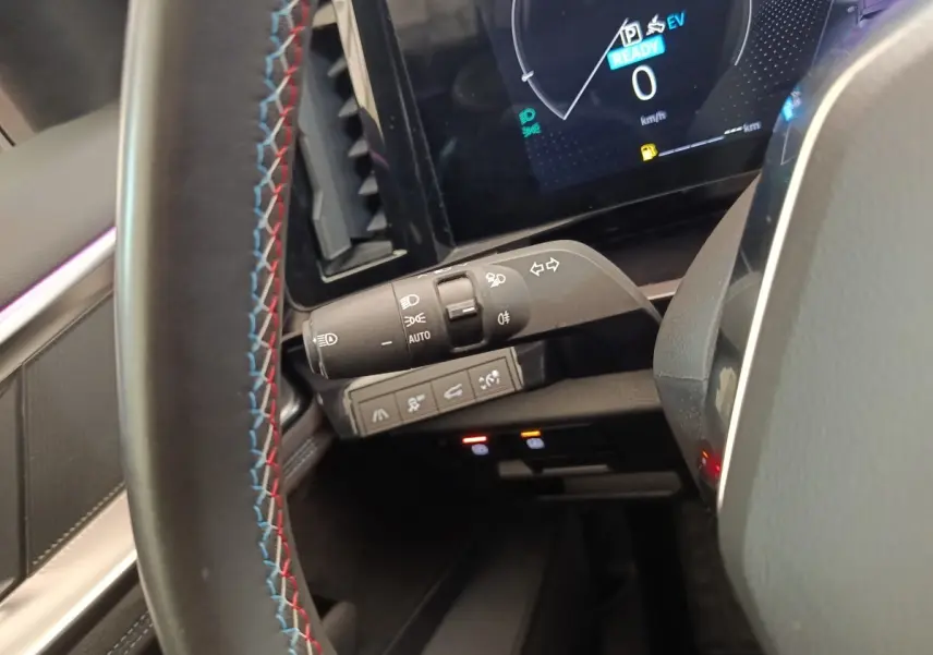 Gros plan intérieur sur la manette de feux et le volant suédé tricolore du Renault Austral gris clair 2024.