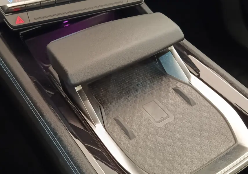 Détail de la console centrale noire du Renault Austral 2024 avec accoudoir et surface de recharge sans fil visible.