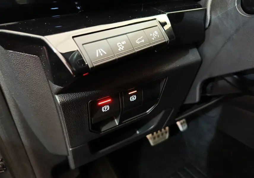Gros plan sur les commandes noires du tableau de bord côté conducteur du Renault Austral gris clair 2024, avec voyants rouges allumés.