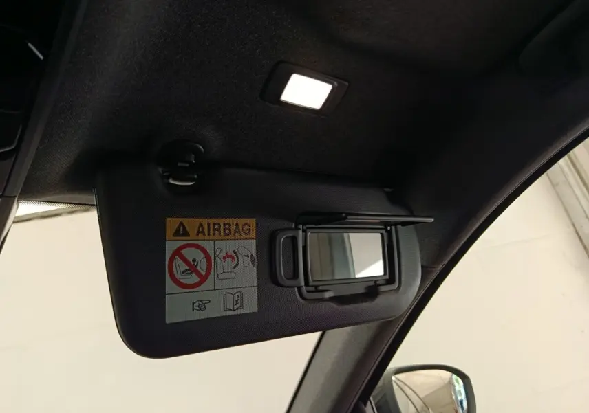 Détail intérieur montrant le pare-soleil gauche avec miroir et avertissement airbag dans un Renault Austral gris clair.
