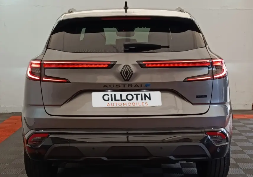 Vue arrière du Renault Austral gris clair 2024 avec feux LED allumés et logo central visible.