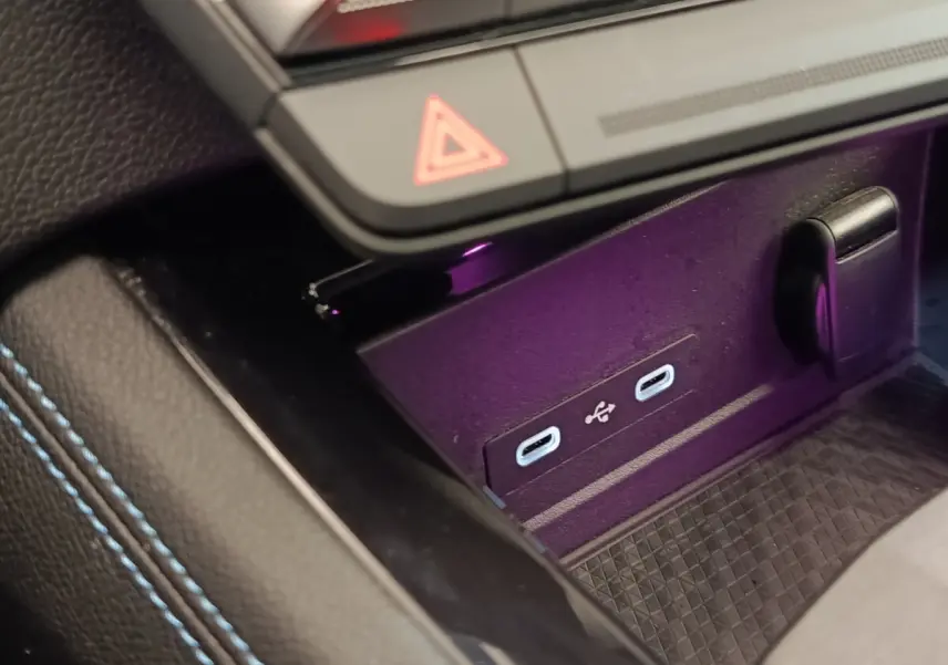 Gros plan sur la console centrale du Renault Austral gris clair, montrant deux ports USB-C et un bouton de signalisation.
