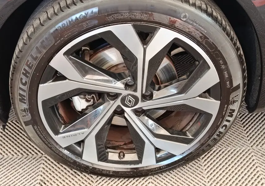 Gros plan sur la jante alu bicolore avec logo Alpine et pneu Michelin Primacy 4 sur Renault Austral gris clair.